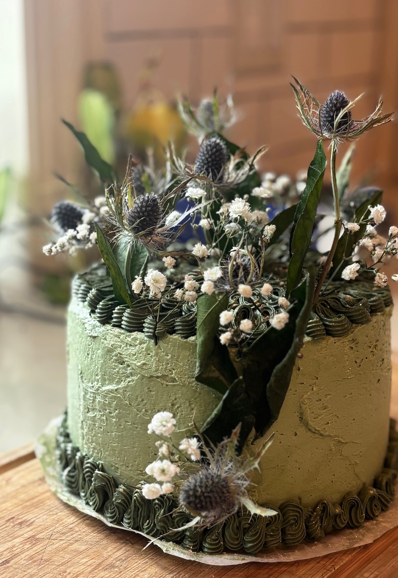 Sage green cake with thistles and baby's breath, side view